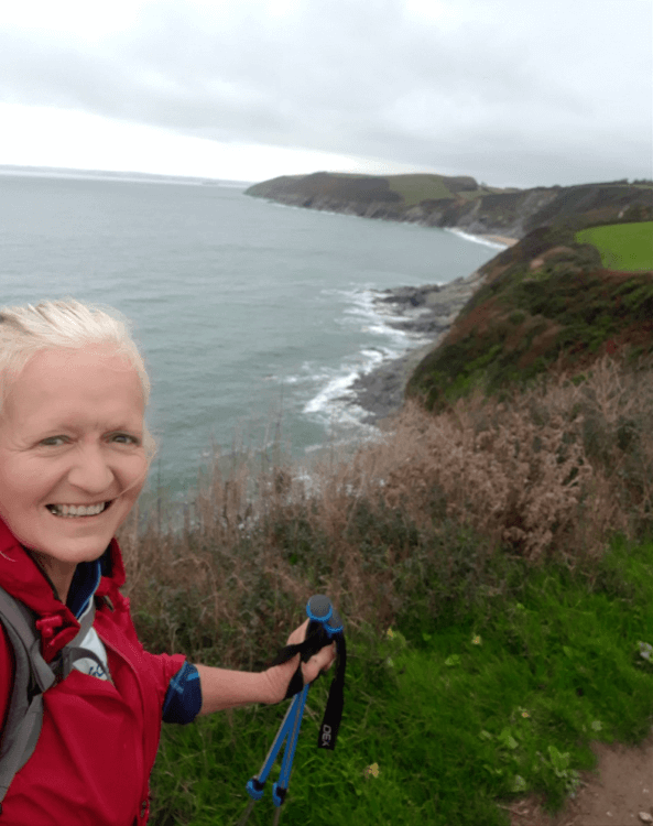 Tracey Hannam grinning at the camera as she hikes the UK Coast Path